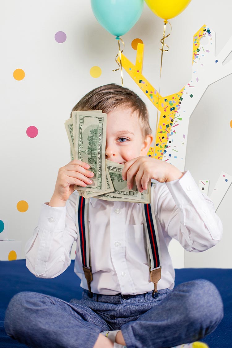 young boy holding dollar bills smiling in a kids birthday party